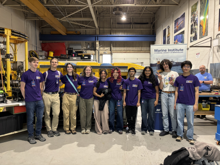 UWROV members and an alum standing in front of a large yellow remotely operated vehicle