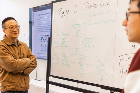 Professor stands arms crossed next to a whiteboard with notes titled "Type 1 Diabetes"