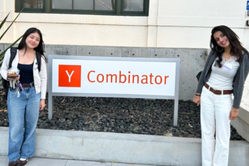 Noelle and Meera flanking the Y Combinator sign.
