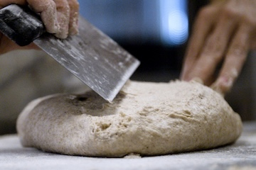 Two hands molding bread dough.