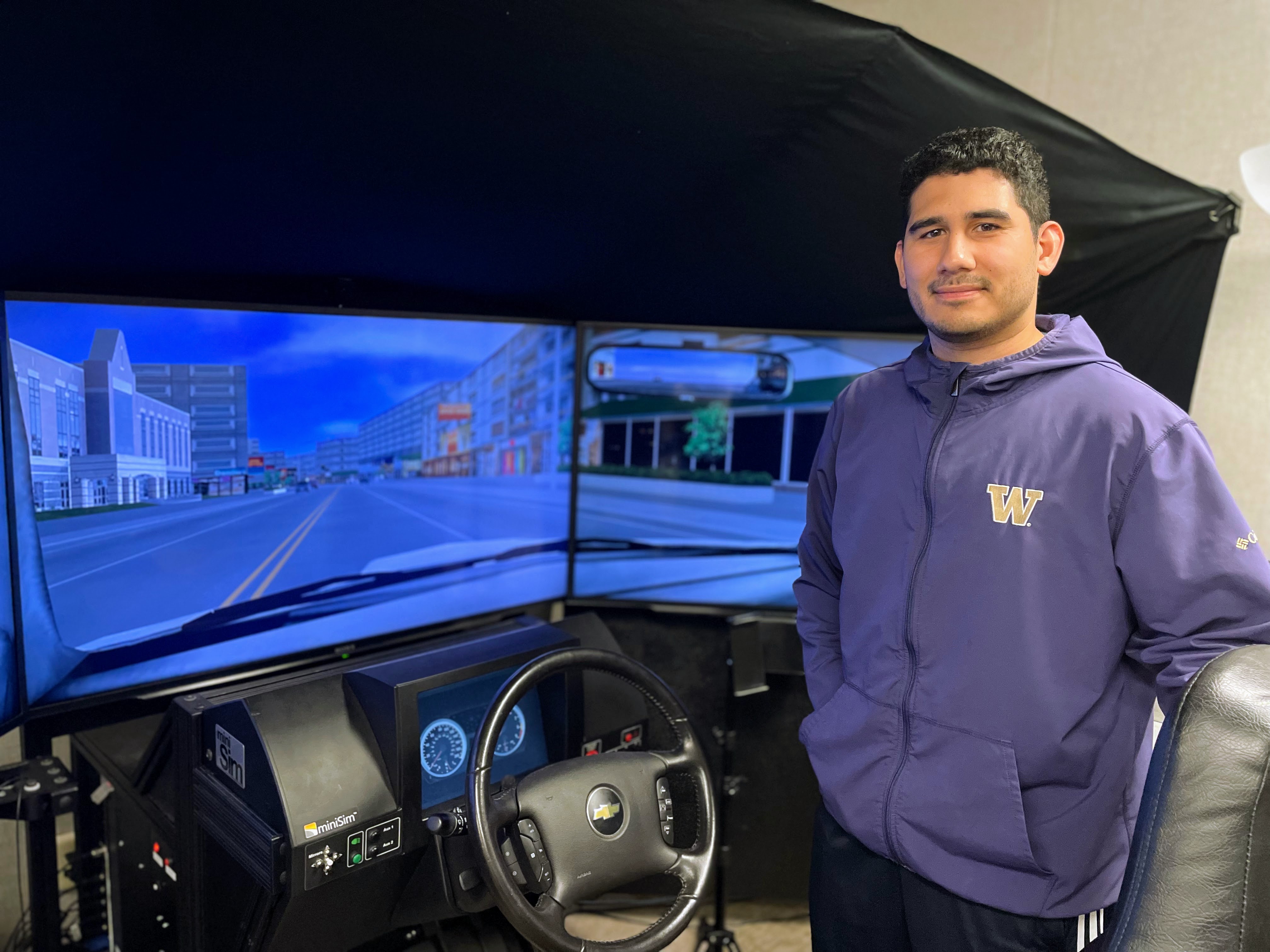 David Prendez smiling next to the car simulator