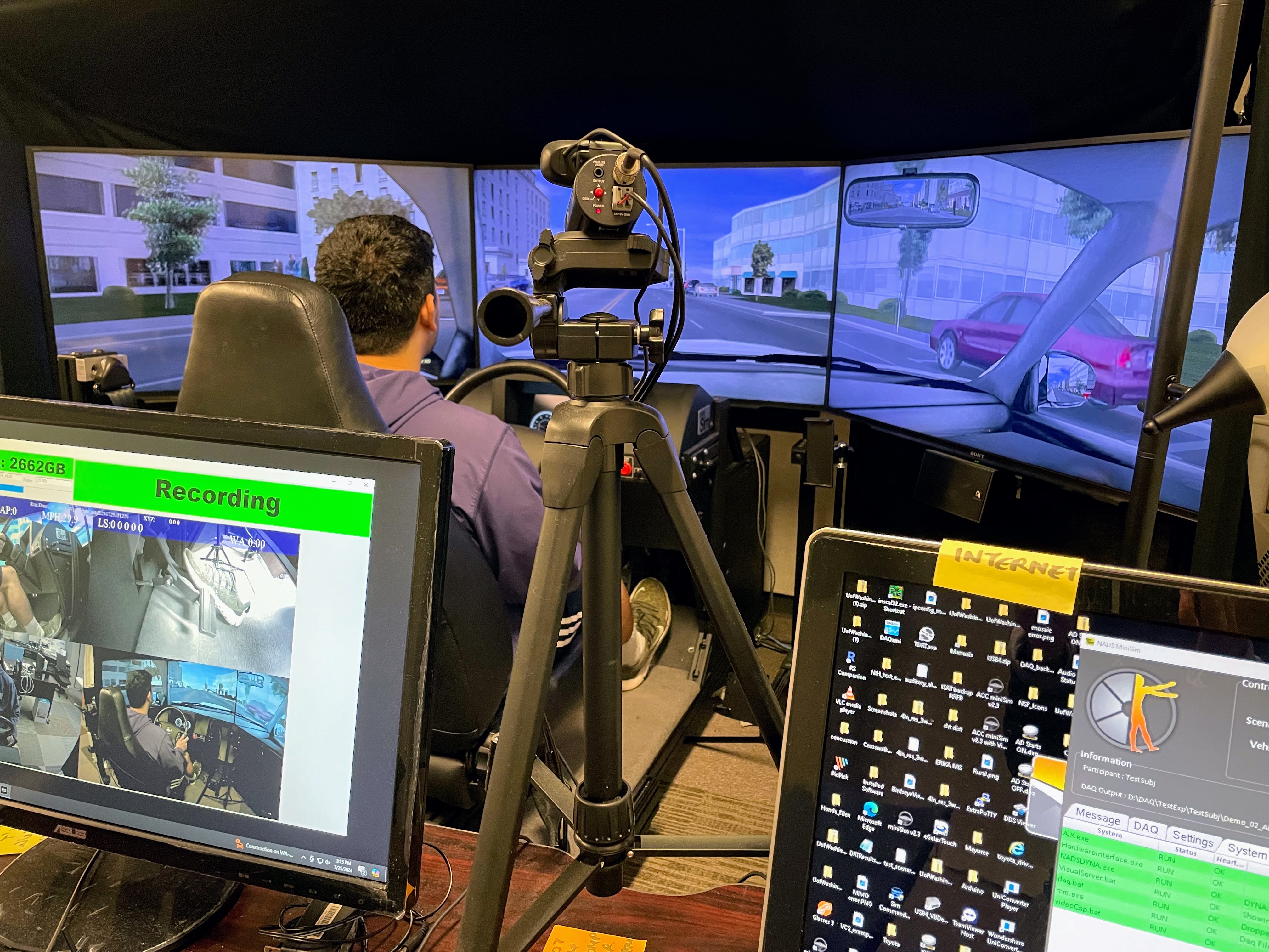 Set up of a driving simulator with computer screens in the foreground.