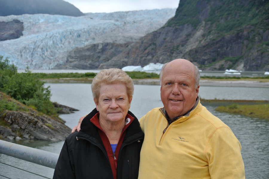 An image showing a woman and a man standing in front of an Alaskan landscape